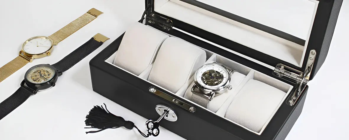 une photo d'une boite a montre en cuir a cote de deux montres une en or et l'autre en noir
